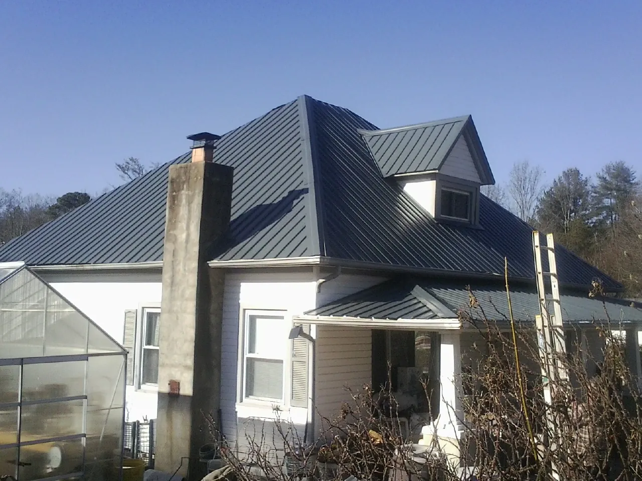 Dark blue standing seam metal roof on a white farmhouse with dormer — Slate & Tile Roof Repair by Roofing Brothers in Killingworth
