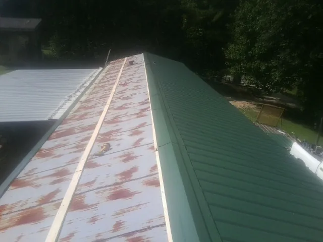 Old rusted panels beside newly installed green metal roofing — Wind Damage Roof Repair by Roofing Brothers in Killingworth