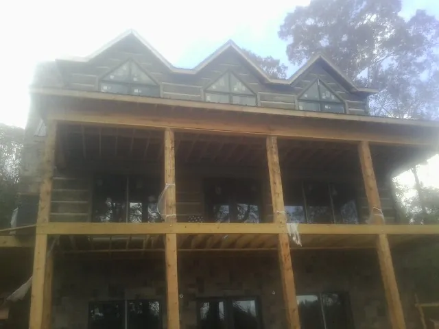 Dormers and porch framing on a large log home under construction — Roof Coating work by our crew in Killingworth