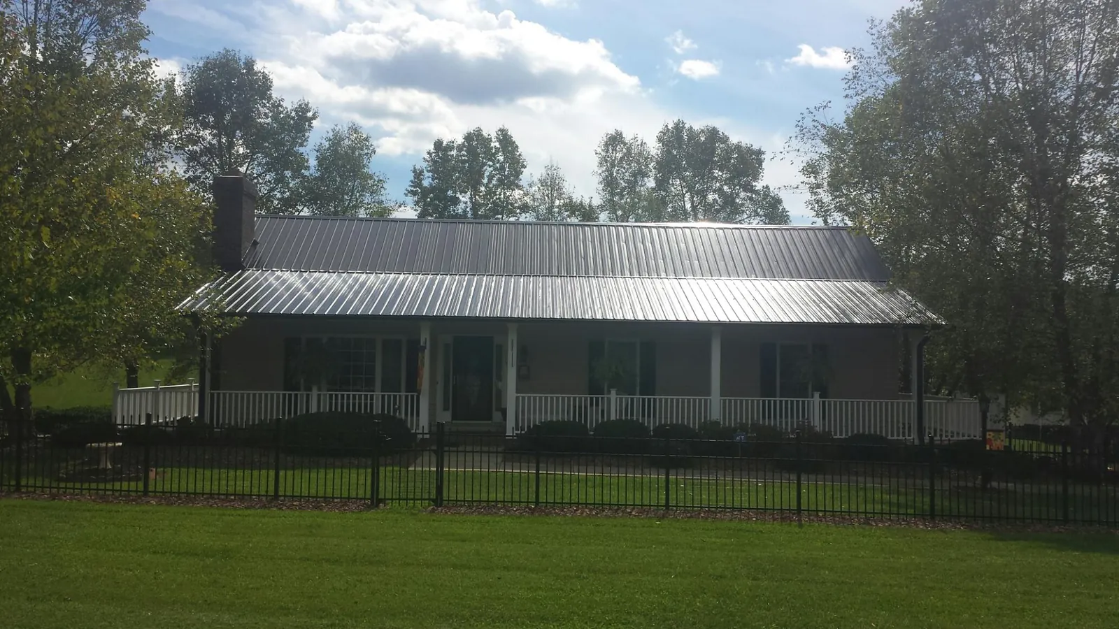 Gray metal roof on a brick ranch with a full width front porch — Gutter Guard Installation work by our crew in Killingworth