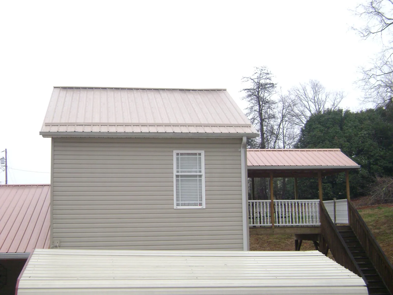 Tan metal roofs on a two story addition and attached porch, from a Roof Replacement job in Killingworth