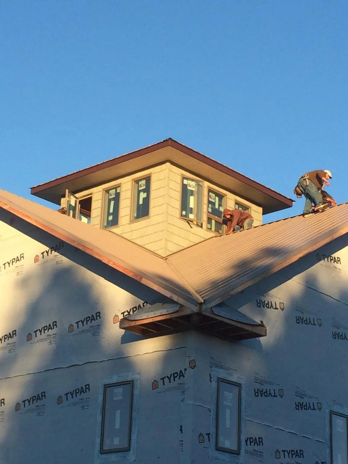Roofers working around a rooftop cupola on a new metal roof at sunset — Roof Waterproofing in Killingworth by Roofing Brothers
